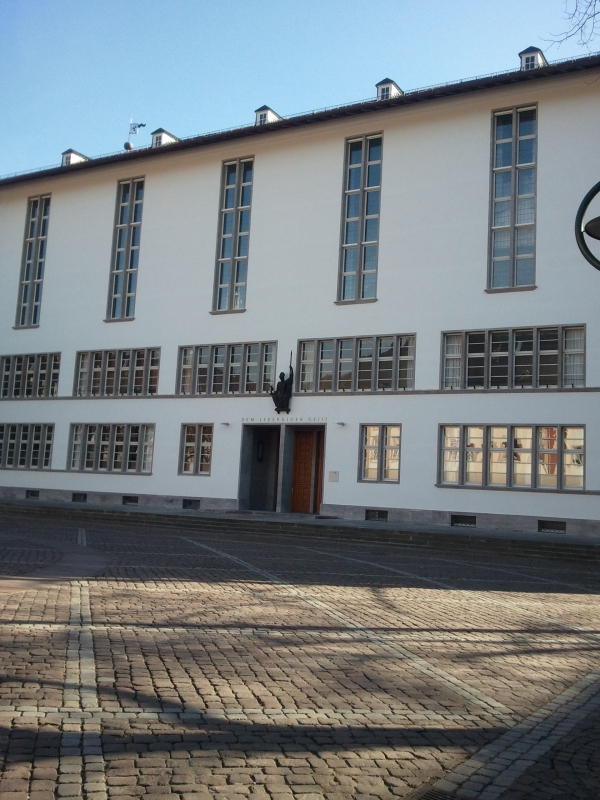 Bild des Eingangs der Neuen Universität. Über dem Eingangsportal prangt der Spruch: &quot;Dem lebendigen Geist&quot; - darüber ist eine Athene Statue angebracht, der Göttin der Weisheit. Während des Nationalsozialismus war die Athene Statue durch einen Reichsadler ersetzt. Der Spruch lautete im Sinne der NS-Ideologie: &quot;Dem deutschen Geiste&quot;