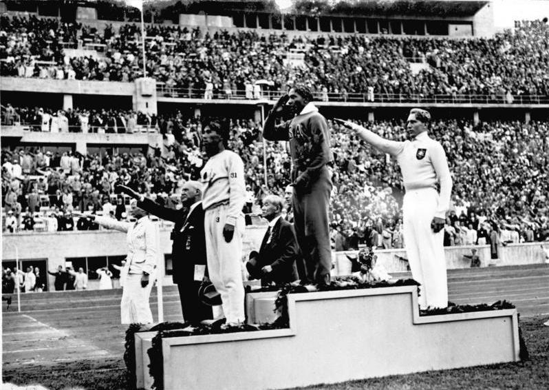 Olympische Spiele 1936 in Berlin, Siegerehrung im Weitsprung: Mitte Owens (USA) 1., links: Tajima (Japan) 3., rechts Long (Deutschland) 2., Zentralbild/Hoffmann Bundesarchiv, Bild 183-G00630 / CC-BY-SA 3.0